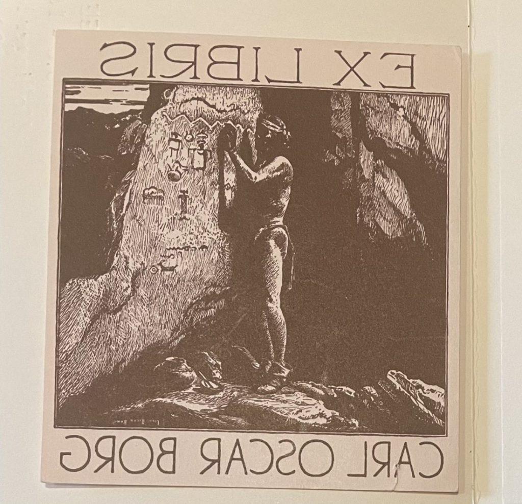 一幅画是一个男人在洞穴墙壁上画人物的黑白图画，旁边的书板上写着“Ex Libris”和“卡尔·奥斯卡·博格”. 
