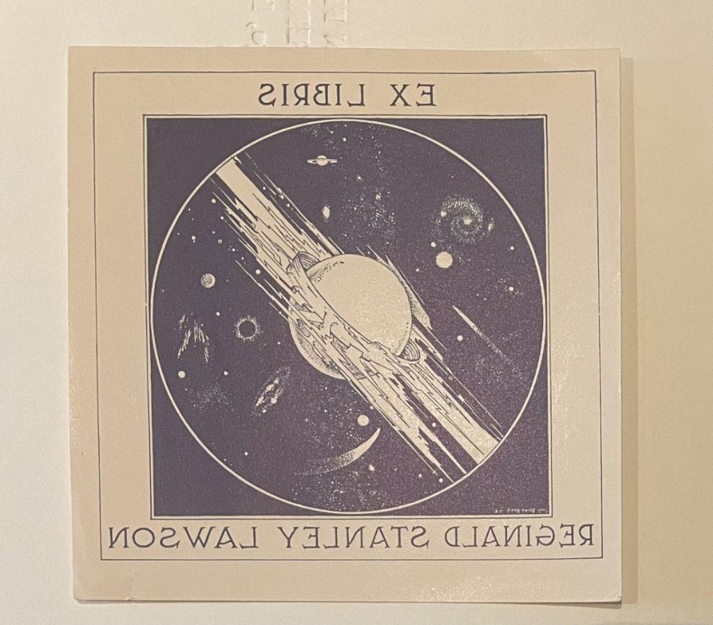 在一幅被彗星包围的行星的黑白图画周围，有一个写着“图书馆”和“雷金纳德·斯坦利·劳森”的书板, 星星, 还有外太空的云.