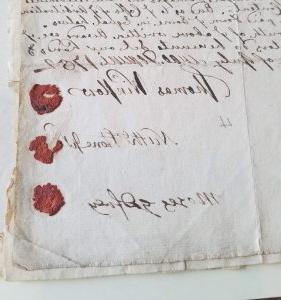 一份手写文件的图像，右下角有三个红色的蜡封. 名字出现在印章旁边.