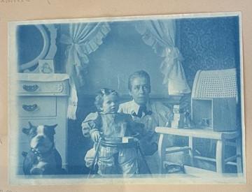 一种浅蓝色的照片，描绘了一个女人、一条狗和一个婴儿一起坐在托儿所里.