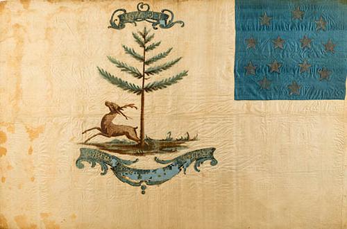 <p>A flag painted on yellowing white silk, somewhat worn. 在左上角是一个正方形的蓝色丝绸，上面有13颗星星排成一个圆圈. 照片中央是一棵松树下一只跳跃的雄鹿. 下面有一个大的圆饰, 轻微脱皮, 上面写着“美国雄鹿”,图片上方较小的圆饰上有首字母“J-G-W-H”.“用金漆的”.</p>
